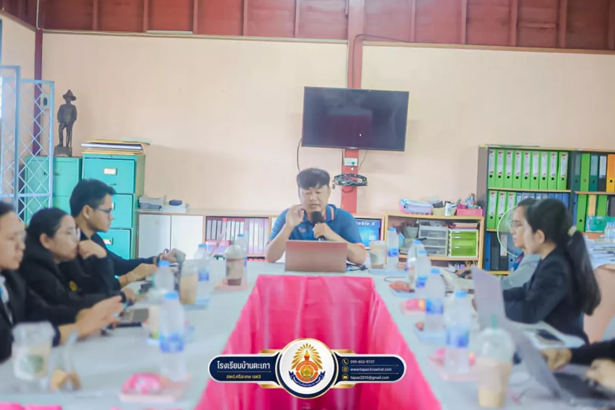 คณะครูโรงเรียนบ้านตะเภานั่งล้อมโต๊ะประชุมเชิงปฏิบัติการถอดบทเรียน พร้อมคอมพิวเตอร์โน้ตบุ๊กและจอนำเสนอ